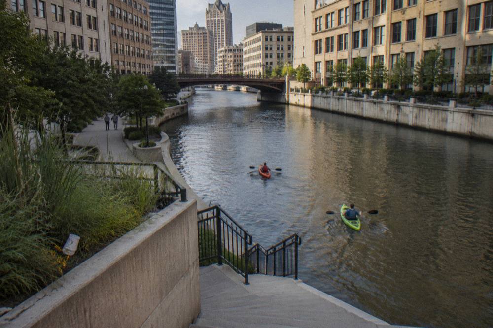 Kayaks floating on the Milwaukee River with downtown buildings rising on both banks