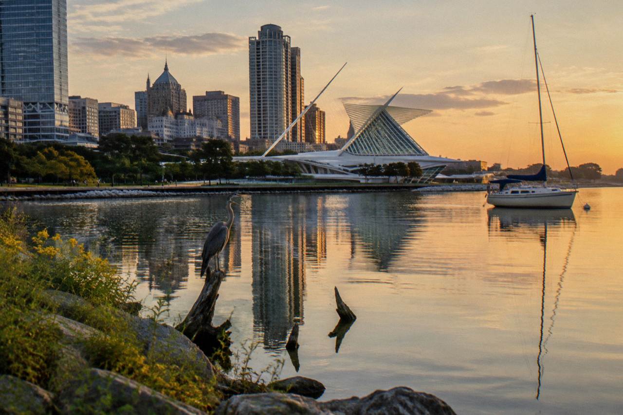 Downtown Milwaukee skyline reflected in the calm Milwaukee River at golden hour