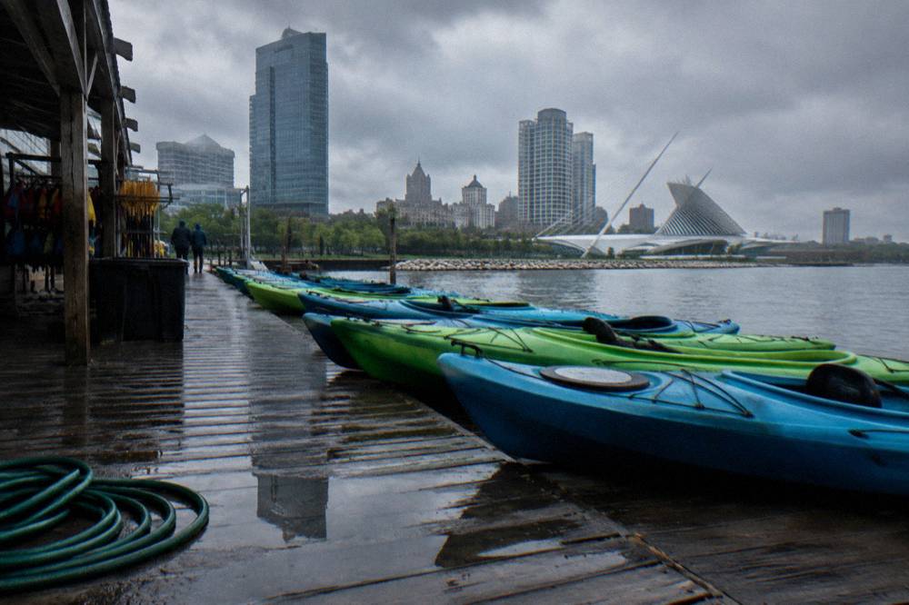 Kayaks lined up on a dock along the Milwaukee River under a cloudy sky