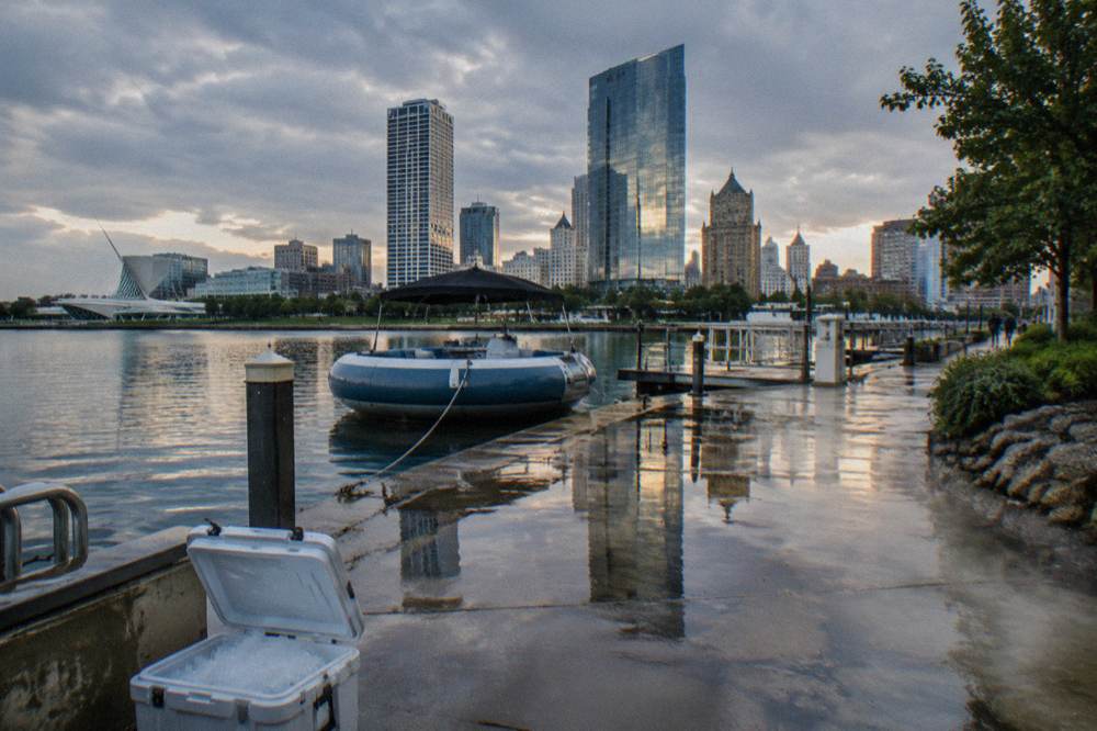 Wet Riverwalk pavement reflecting downtown Milwaukee buildings after rain