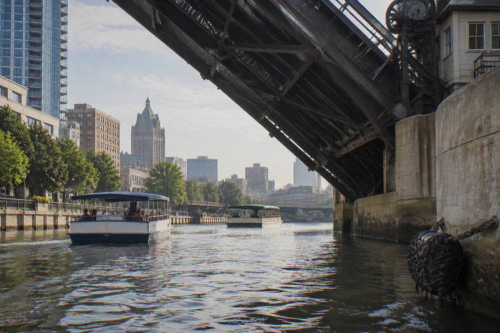 A drawbridge leaf raised over the Milwaukee River with boats waiting in the channel
