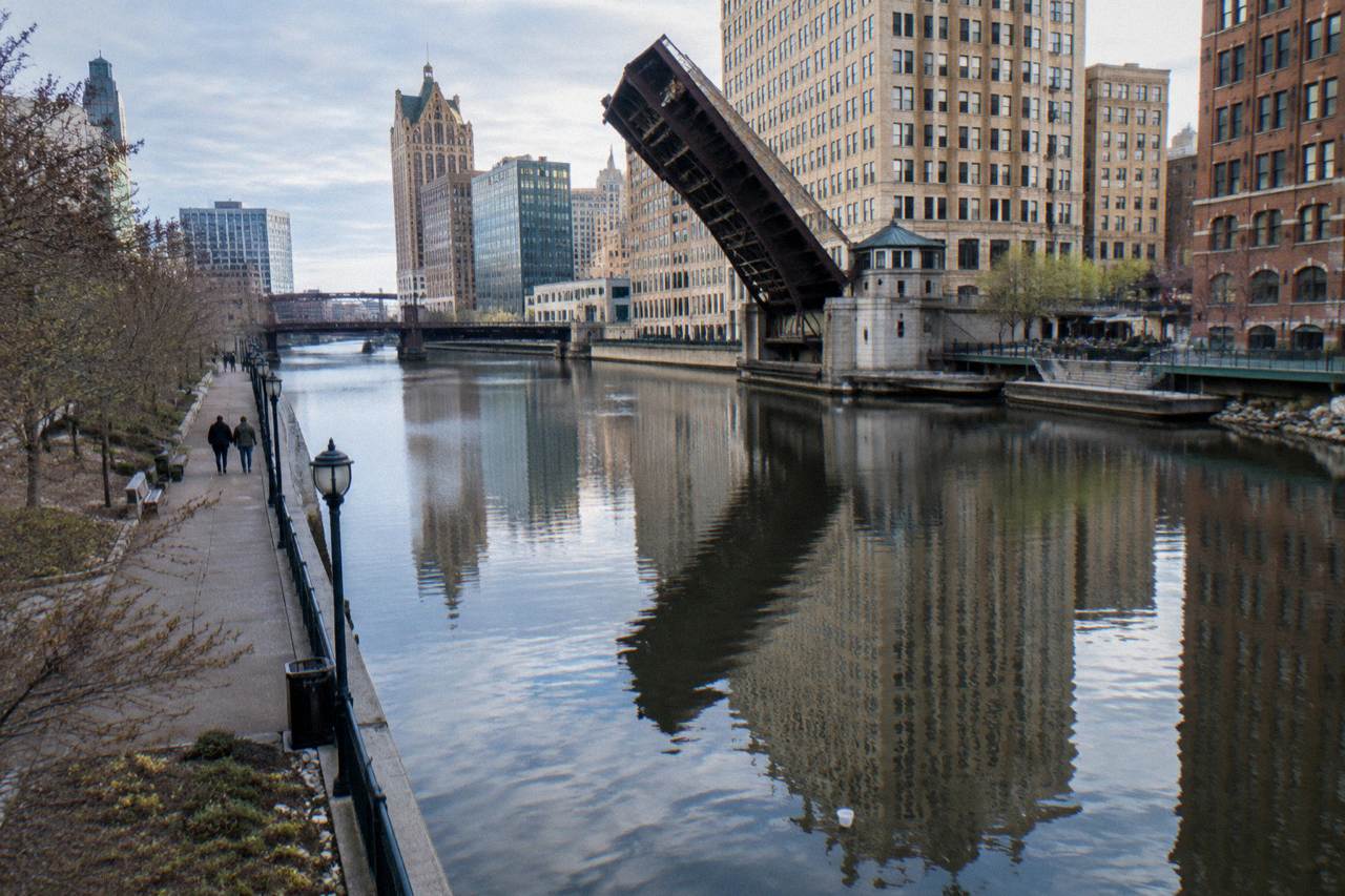 A bascule bridge over the Milwaukee River with downtown buildings reflected in the water