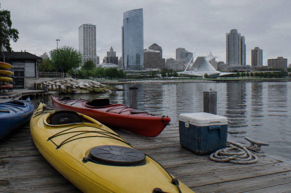 Kayaks resting on a dock in the Milwaukee harbor with calm lake water beyond