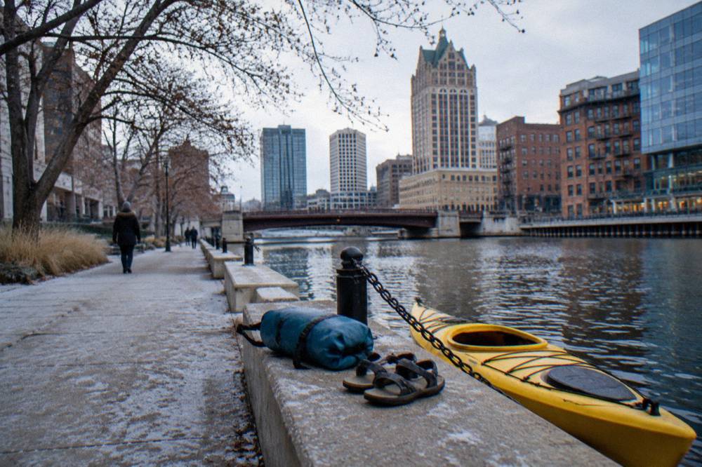 Sandals and a dry bag resting on a wooden dock beside a kayak