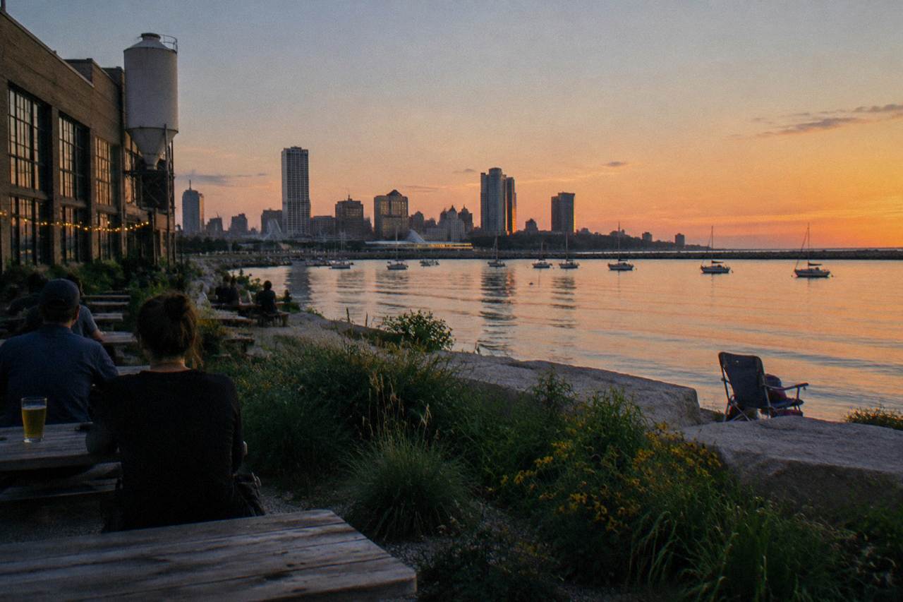 Boats anchored on calm water at dusk with a city skyline across the horizon