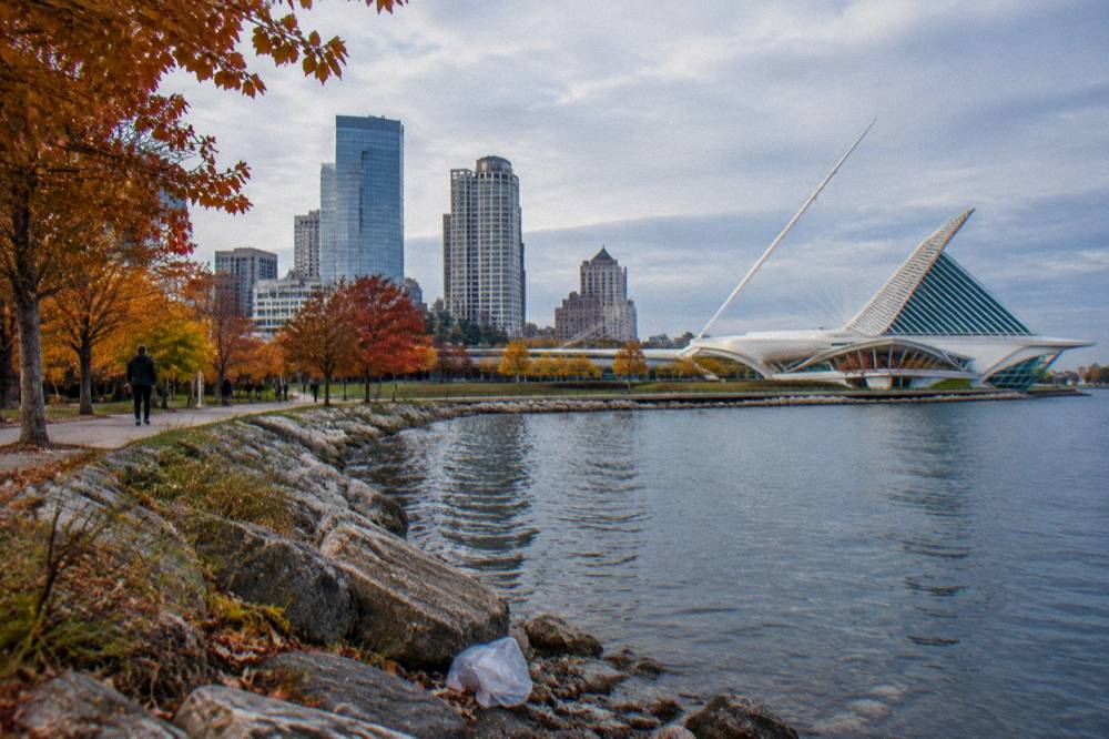 Fall color in trees along the Milwaukee River banks with downtown buildings beyond