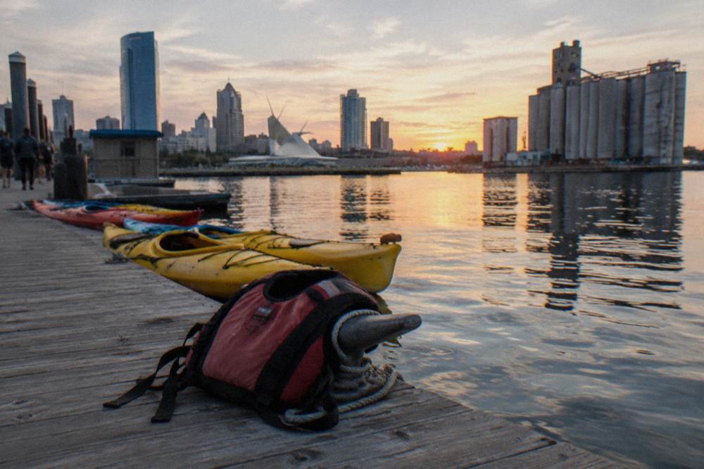 Kayaks resting on a dock in the Milwaukee Harbor District with the river behind