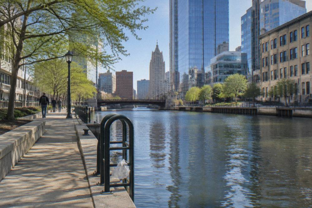 Calm stretch of the Milwaukee River between downtown buildings on a bright morning