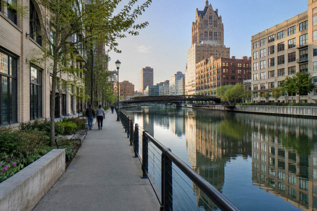 Riverwalk path along the Milwaukee River with downtown buildings reflected in the water