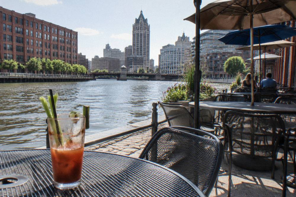 Restaurant patios along the Milwaukee River with tables facing the water