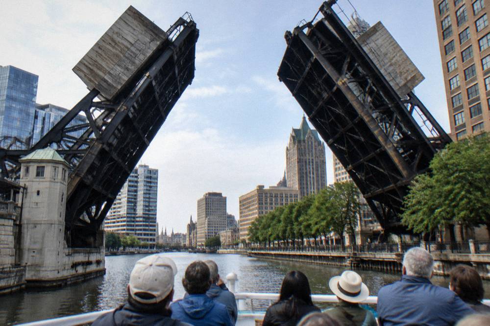 Passenger cruise boat traveling under a raised bascule bridge on the Milwaukee River