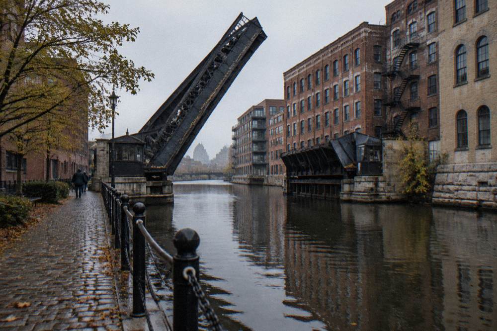 A bascule bridge spanning the Milwaukee River between old brick downtown buildings