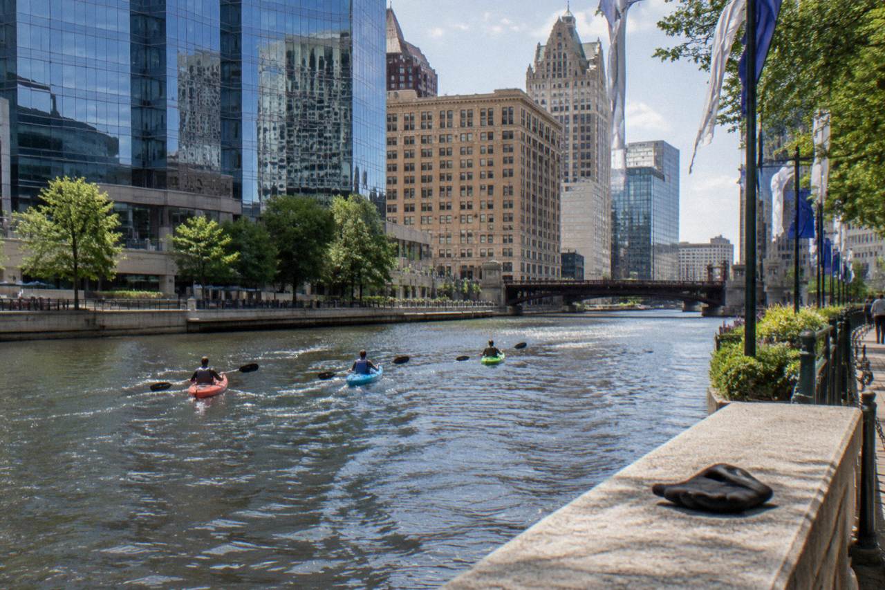 Kayaks floating on the Milwaukee River beside downtown buildings on a bright afternoon
